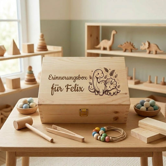 Personalisierte Erinnerungsbox aus Holz mit dem Namen Felix und Gravur mit Dinosaurier-Motiv, umgeben von Holzspielzeug im Montessori-Stil auf einem Kindertisch.