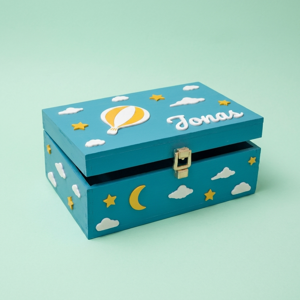 Erinnerungsbox in Tealblau mit dem Namen Jonas, personalisiert mit Heißluftballon, Wolken und Sternen. Dreiviertelansicht, pastellgrüner Studiohintergrund.