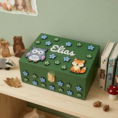 Erinnerungsbox aus grünem Holz, personalisiert mit dem Namen Elias, verziert mit Waldtieren in Relief, darunter eine Eule und ein Fuchs, Blätter und blaue Blumen.