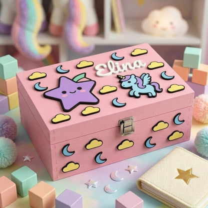 Personalisierte rosa Holzbox für Mädchen mit dem Namen Elina als weißes Relief, dekoriert mit 3D-Applikationen im magischen Stil: hellblaues Einhorn, lila lächelnder Stern, blaue Monde und gelbe Wolken.