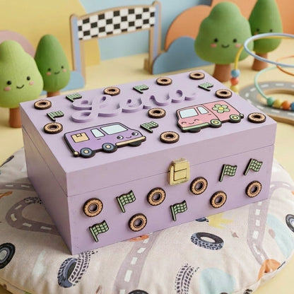 Personalisierte Erinnerungsbox aus lila Holz für Kinder mit dem Namen Lena in Relief, dekoriert mit Lieferwagen, Rädern und Schachbrettfähnchen.