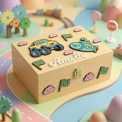 Personalisierte Erinnerungsbox aus Holz mit dem Namen Amelie in Relief, dekoriert mit 3D-Applikationen eines gelben Monster-Trucks, eines türkisfarbenen U-Boots, rosa Wölkchen und Schachbrettfähnchen.