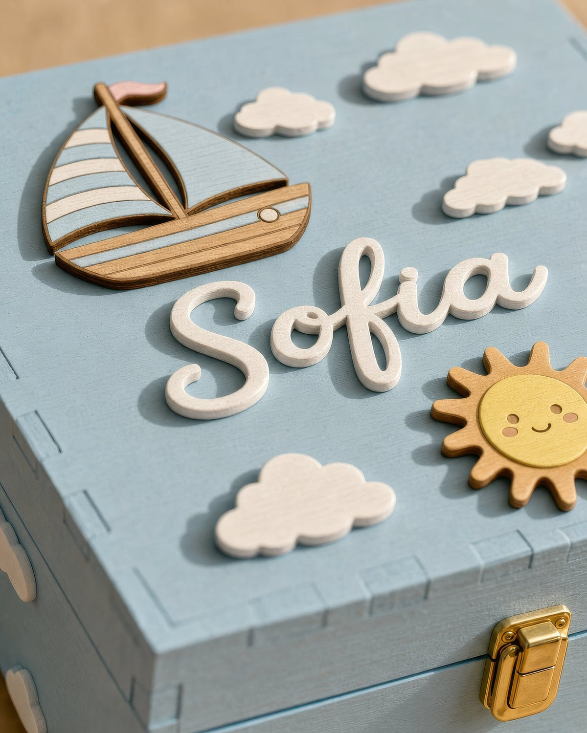 Name Sofia in weißer Holzschreibschrift im Relief auf dem hellblauen Deckel, mit Boot, Sonne und Wölkchen