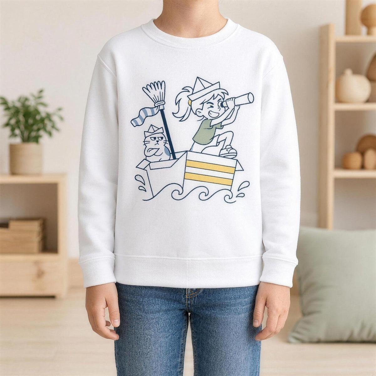 Mädchen im weißen Kinder-Sweatshirt mit dem Motiv „Die Kapitänin“, in einem hellen Spielzimmer