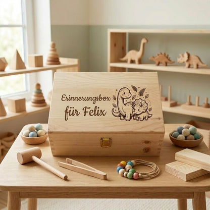 Personalisierte Erinnerungsbox aus Holz mit dem Namen Felix und Gravur mit Dinosaurier-Motiv, umgeben von Holzspielzeug im Montessori-Stil auf einem Kindertisch.